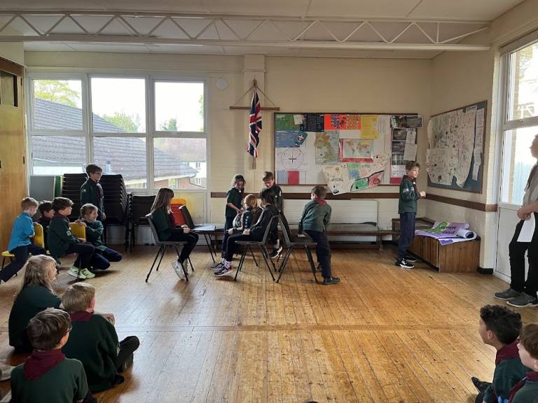 Photograph of a group of cubs using chairs to pretend to be on a train