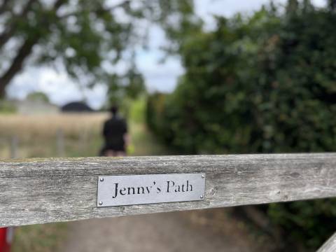 Image of the gate to Jenny's path in Shelford. The background is blurred but a walker can be seen.